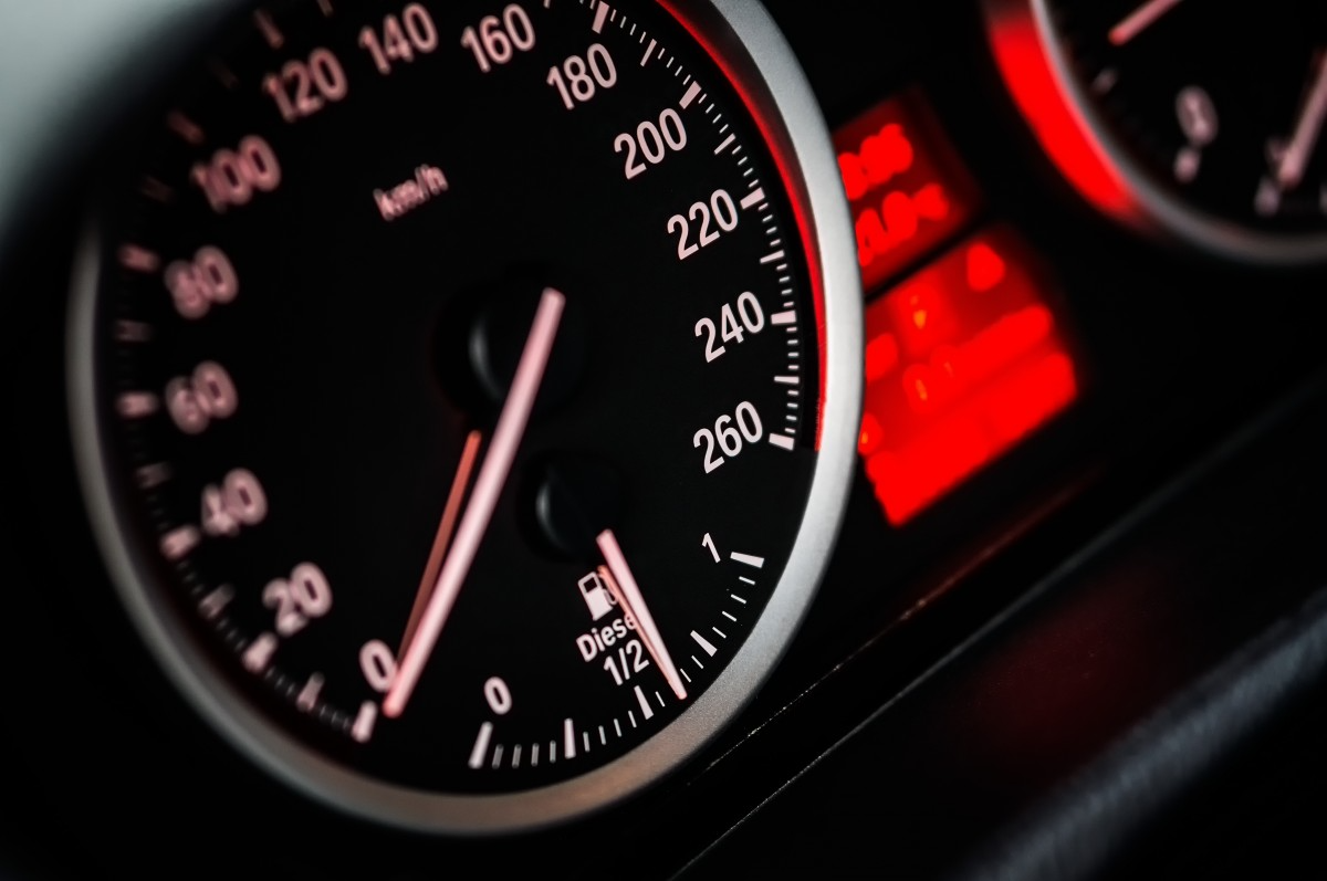 Close-up of a car's speedometer, showing speeds from 0 to 260 km/h, with glowing red indicators and diesel fuel gauge at half.