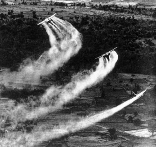 Three aircraft releasing trails of chemical clouds over a rural landscape, with visible fields and trees below, suggesting an aerial operation.