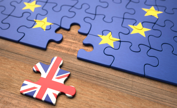 Blue puzzle with yellow stars representing the EU flag, missing a piece. The missing piece below displays the UK flag, symbolising Brexit.