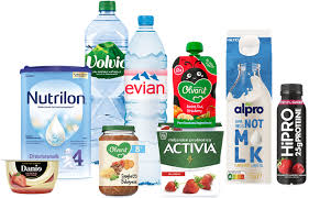 Assorted food and drink products including bottled water, yoghurt, plant-based milk, baby food, and protein shake, arranged against a white background.