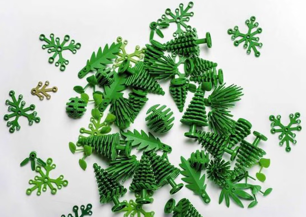 Assorted green plastic pieces shaped like trees and snowflakes scattered on a white surface.
