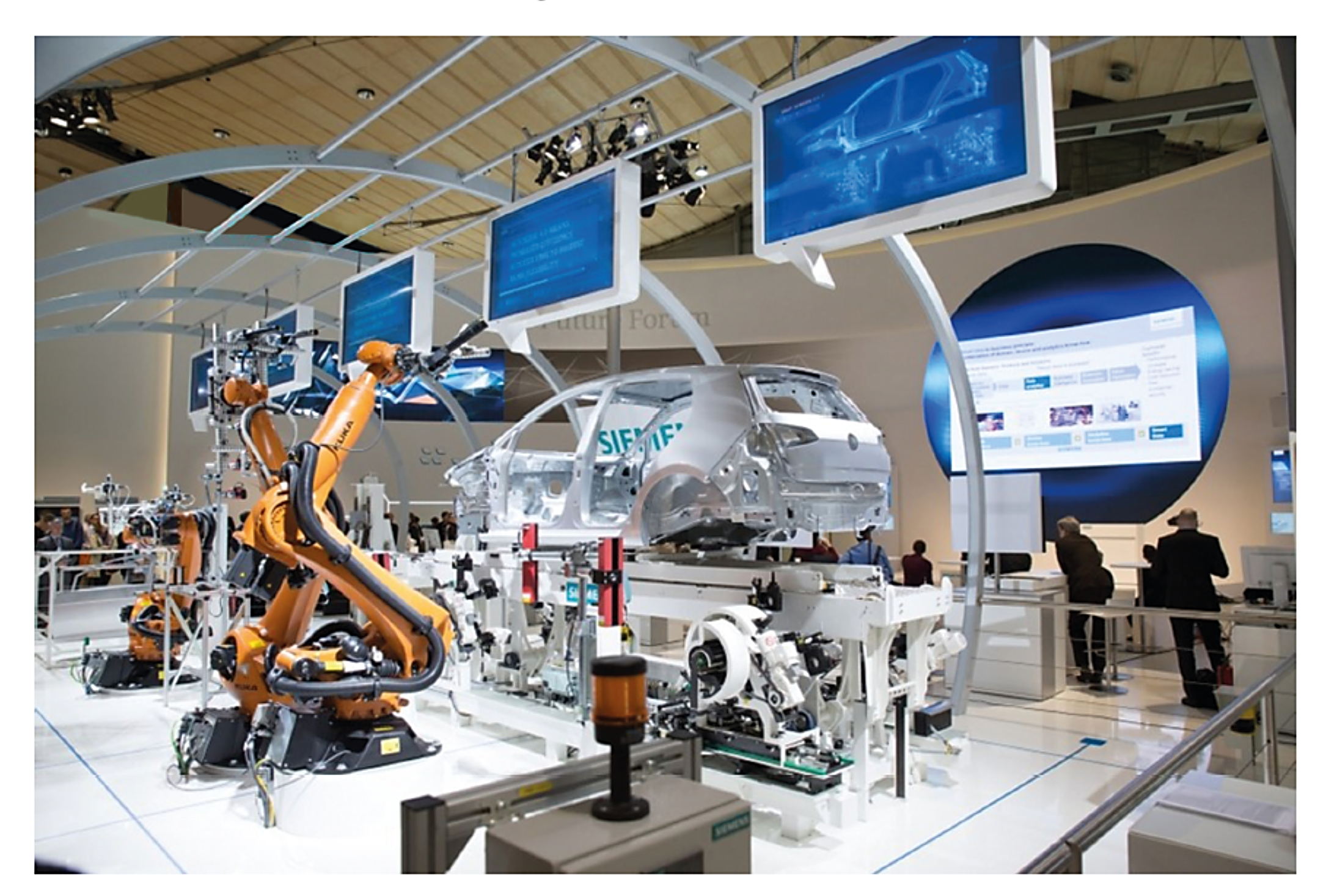 Robotic arms assembling a car frame at an exhibition with screens displaying automotive information, people observing in the background.
