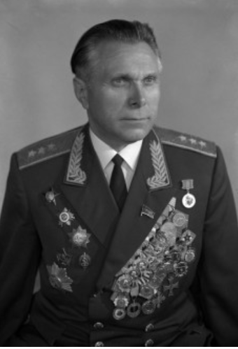Man in military uniform adorned with numerous medals and decorations, facing forward with a neutral expression, against a plain background.