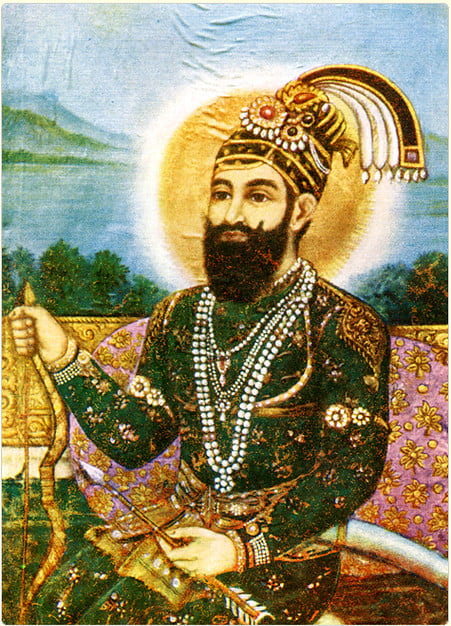 A richly dressed image of Guru Gobind Singh with a turban and beaded necklaces sits holding a staff, with a glowing halo behind, set against a scenic landscape background.