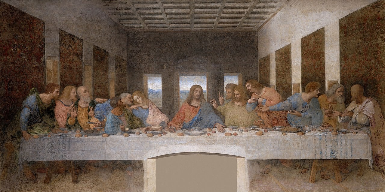 Thirteen figures seated at a table, centred by a figure in flowing robes, in a large, dimly lit room with a coffered ceiling and mountain view.