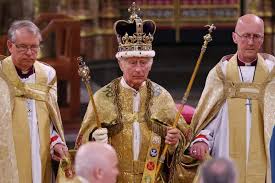 A man wearing a gold robe and crown holds a sceptre and orb, flanked by two robed men in a formal, ornate setting.