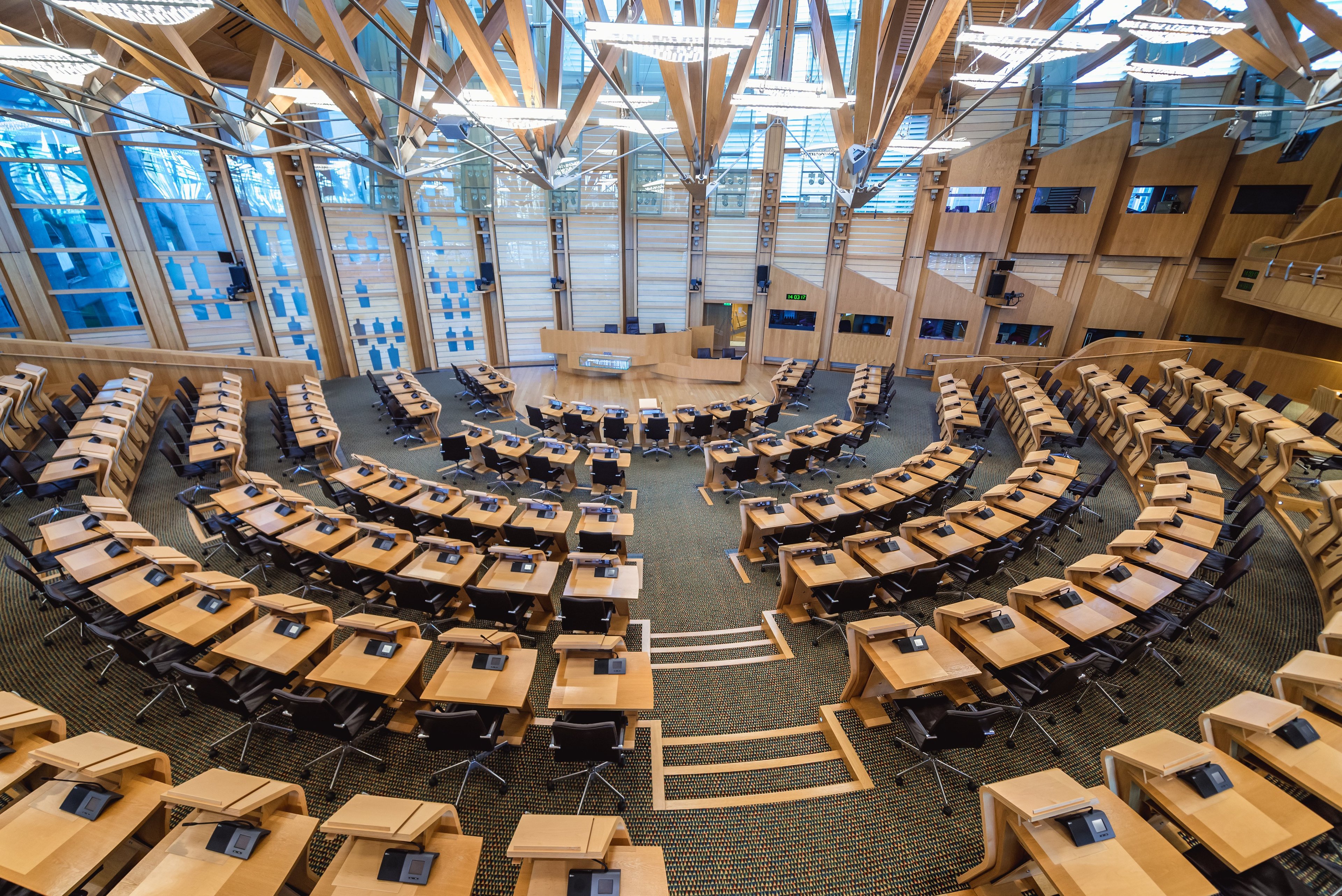 A modern debating chamber, with desks formed in a horseshoe around a central platform