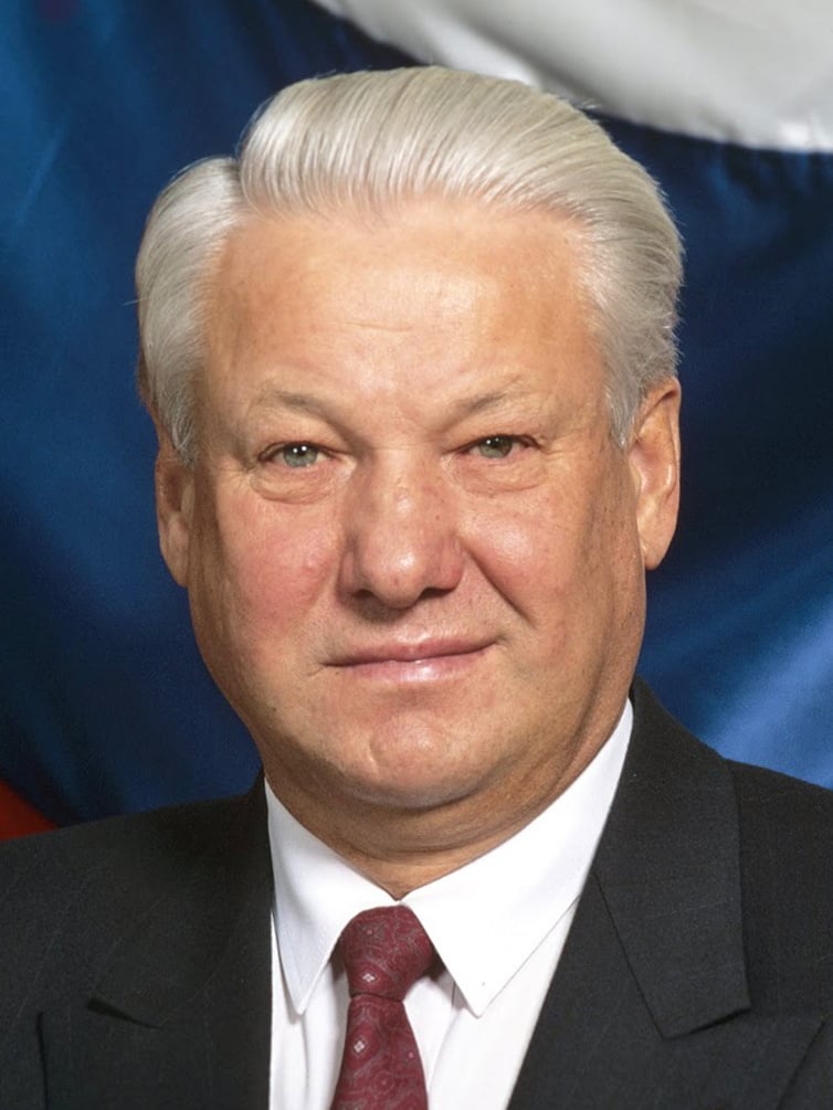 An image of Boris Nikolayevich Yeltsin, the President of Russia. The image shows an elderly man in a suit with white hair, standing against a background resembling a flag with blue, white, and red colours.