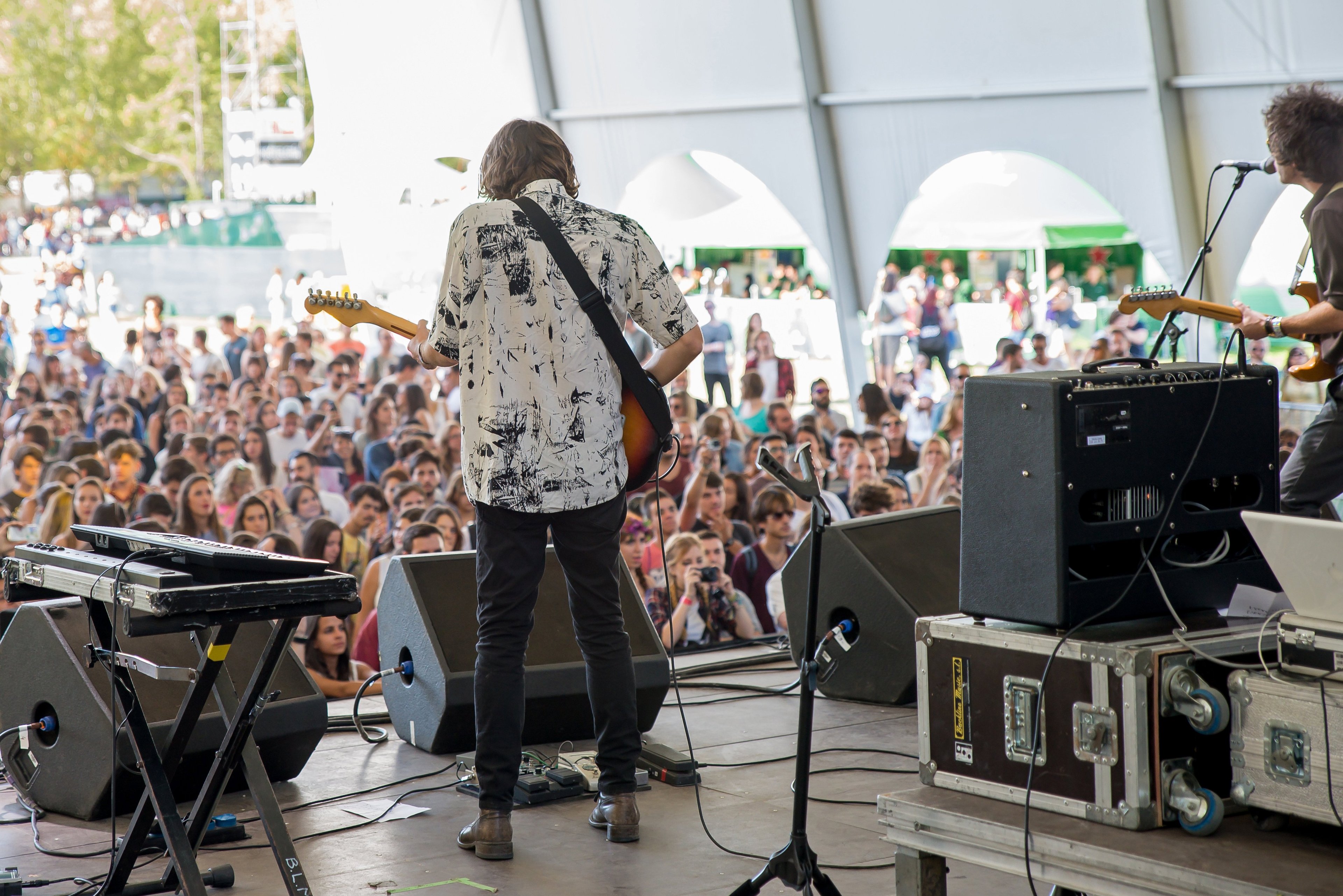 music festival, large crowd, music group onstage, musical instruments on stage, nice weather/outside
