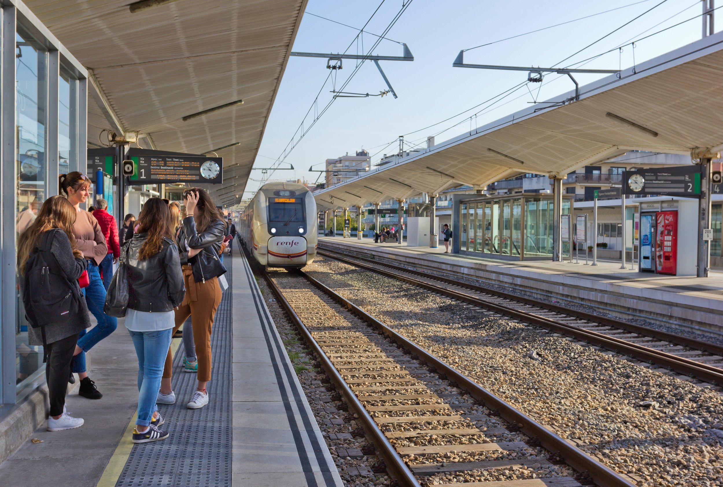 An image which shows people waiting for a train on a nice day. Make sure if there’s any writing (like names of places), that it’s in Spanish. This needs to be a photo rather than an illustration.