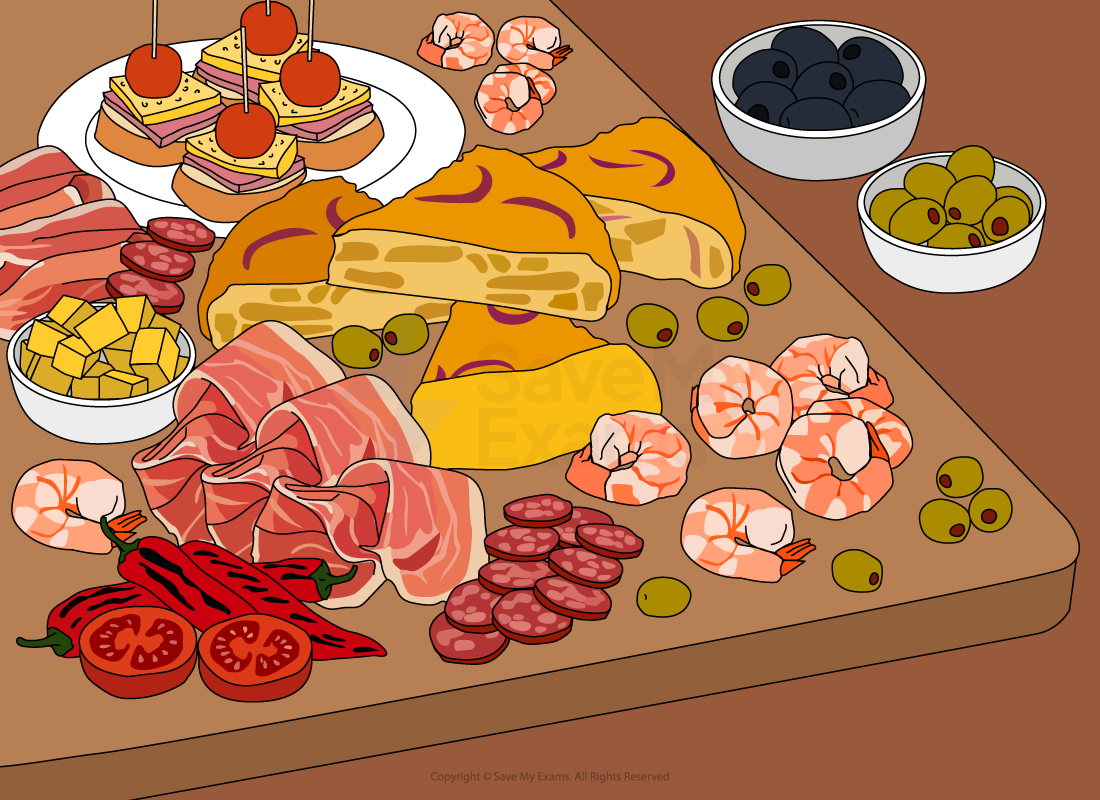 A tapas platter with assorted meats, cheeses, olives, prawns, sliced tomatoes, red peppers, and skewered bites on a wooden board.