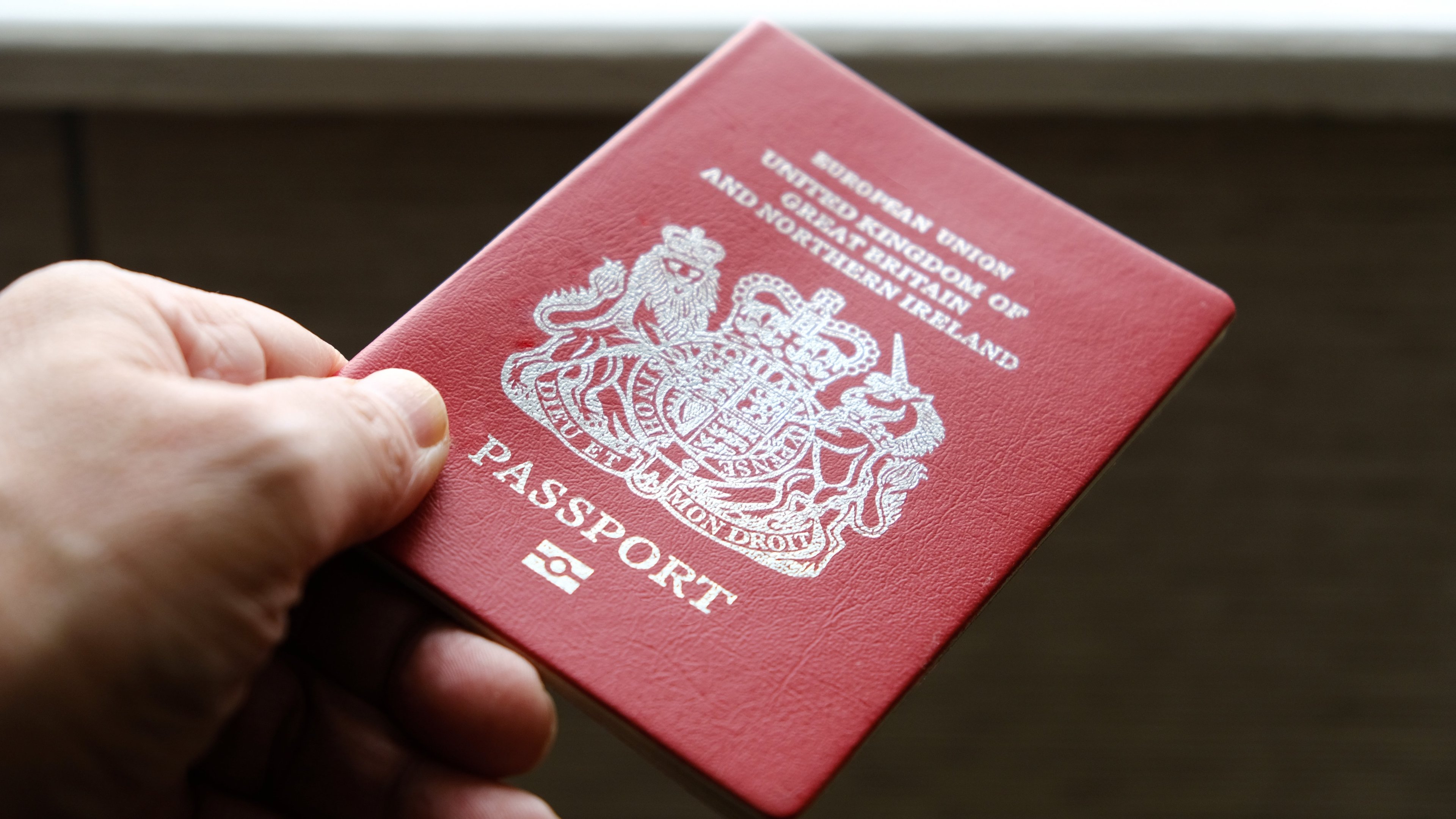 A hand holding out a UK passport