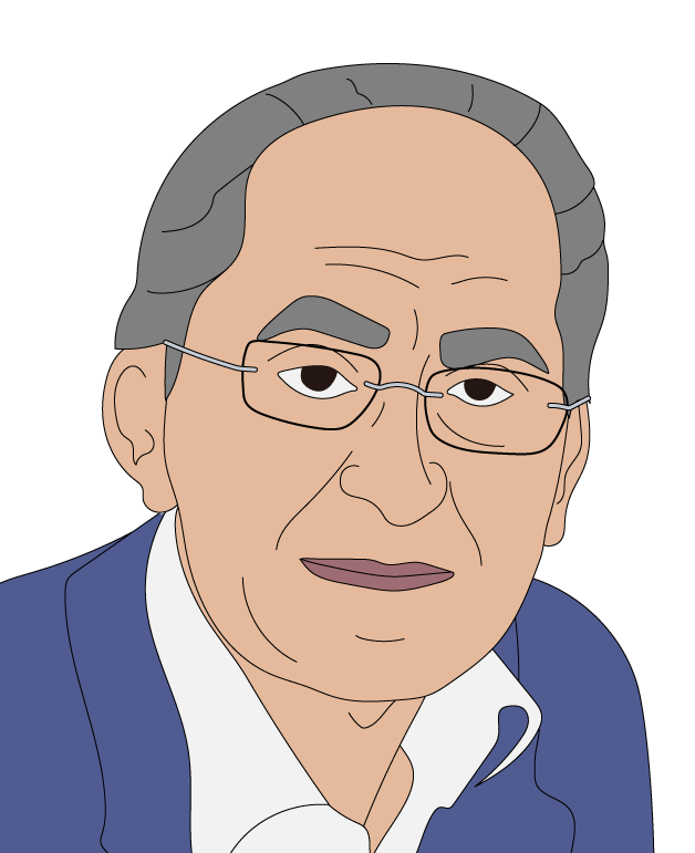 Smiling man in glasses and a light shirt sits in front of a bookshelf filled with various books, creating an academic and relaxed ambience.