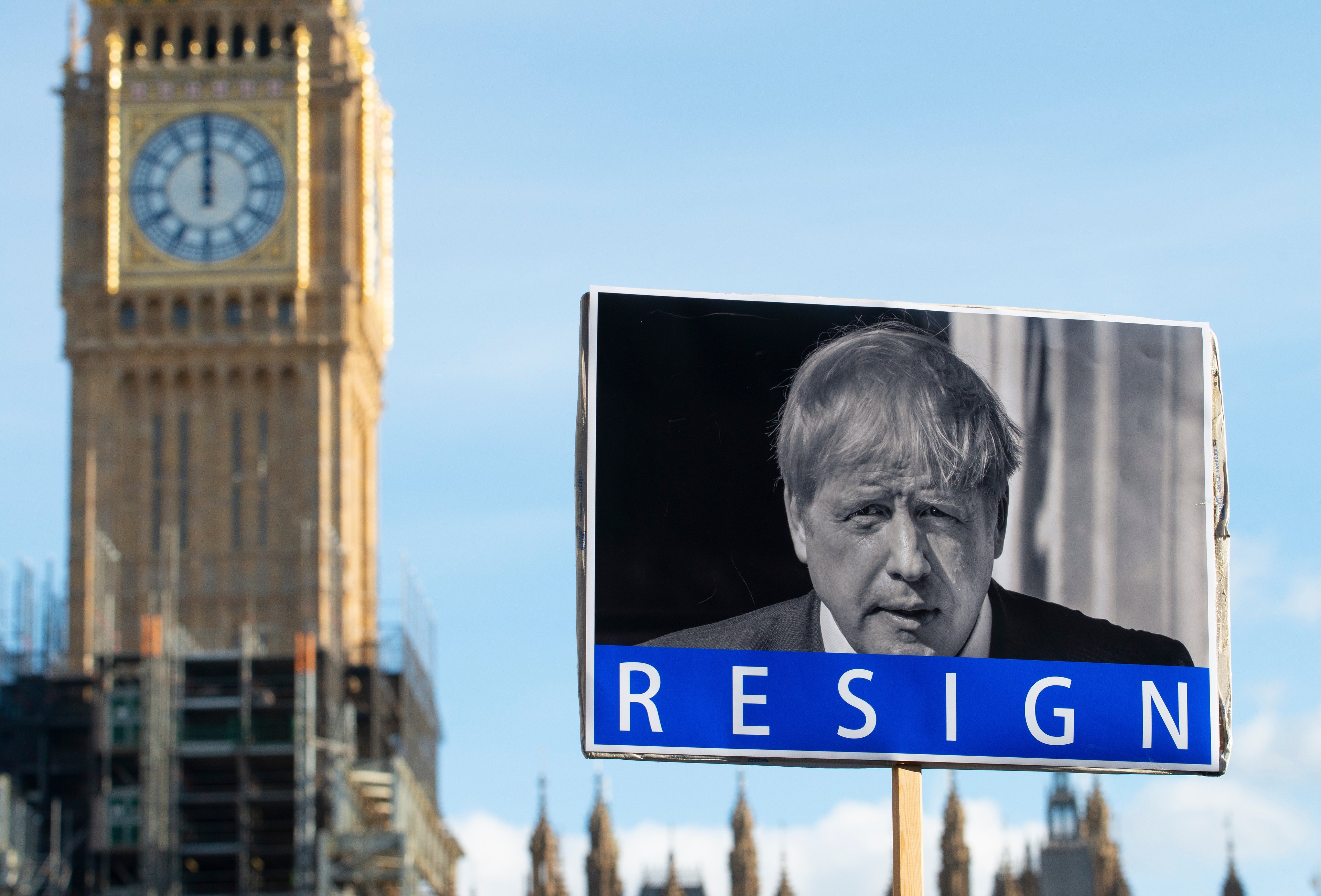 A background of Big Ben, with a banner containing an image of Boris Johnson and the word Resign