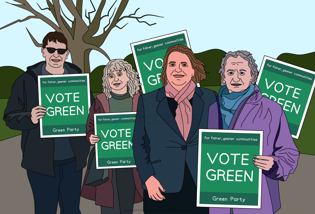 Four people stand holding "Vote Green" signs for the Green Party, advocating fairer, greener communities. A tree and hills are in the background.