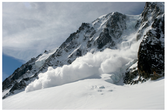 Snow avalanche descending a steep, rugged mountain with a cloudy sky backdrop, showcasing the power and dynamics of snow movement.