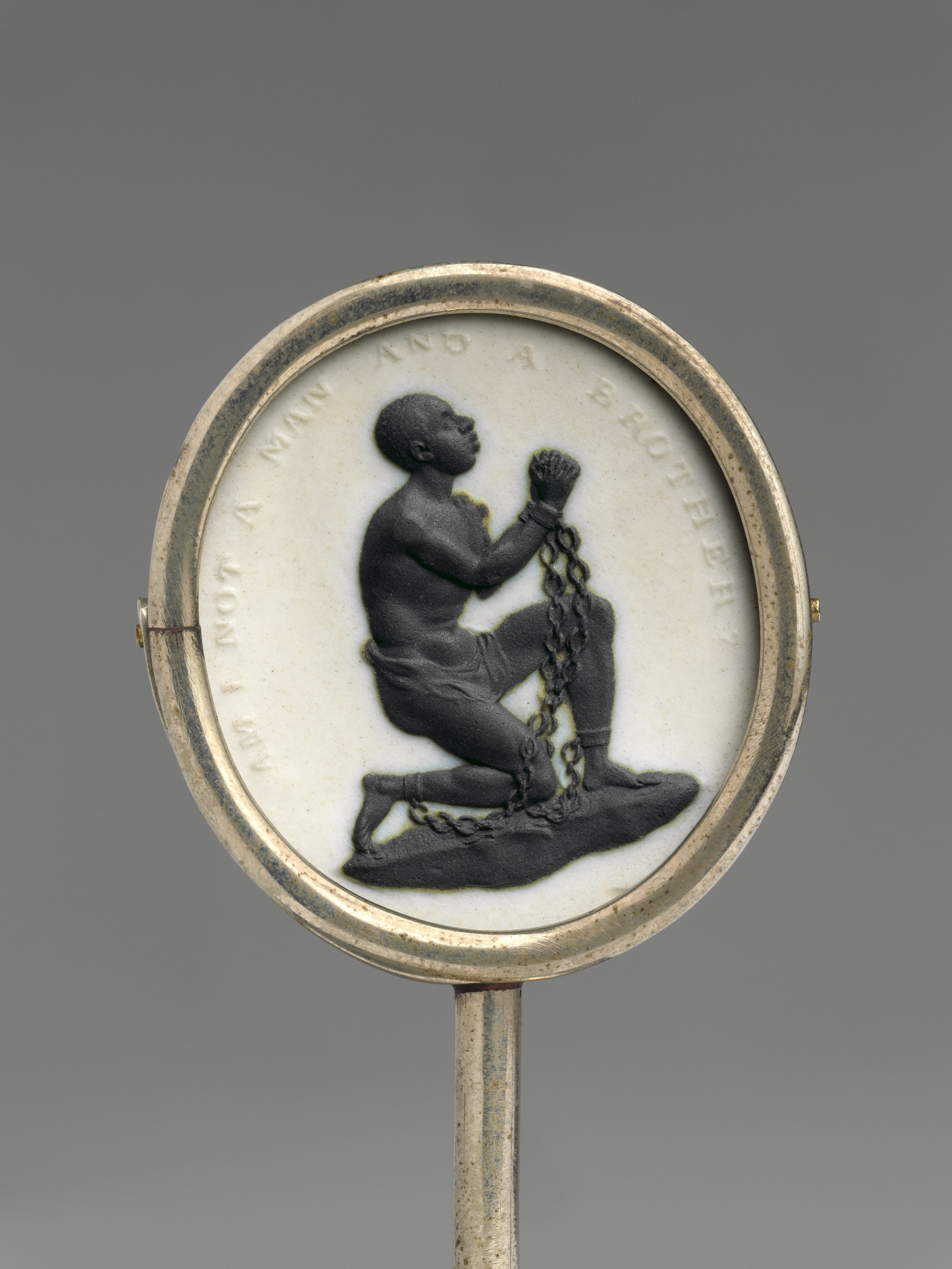 A medallion depicting a kneeling, shackled figure in profile, with the inscription "Am I not a man and a brother?" on a circular background.