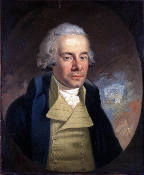 Portrait of a man with white hair, wearing a dark coat over a cream waistcoat and white cravat, set against a dark, oval background.