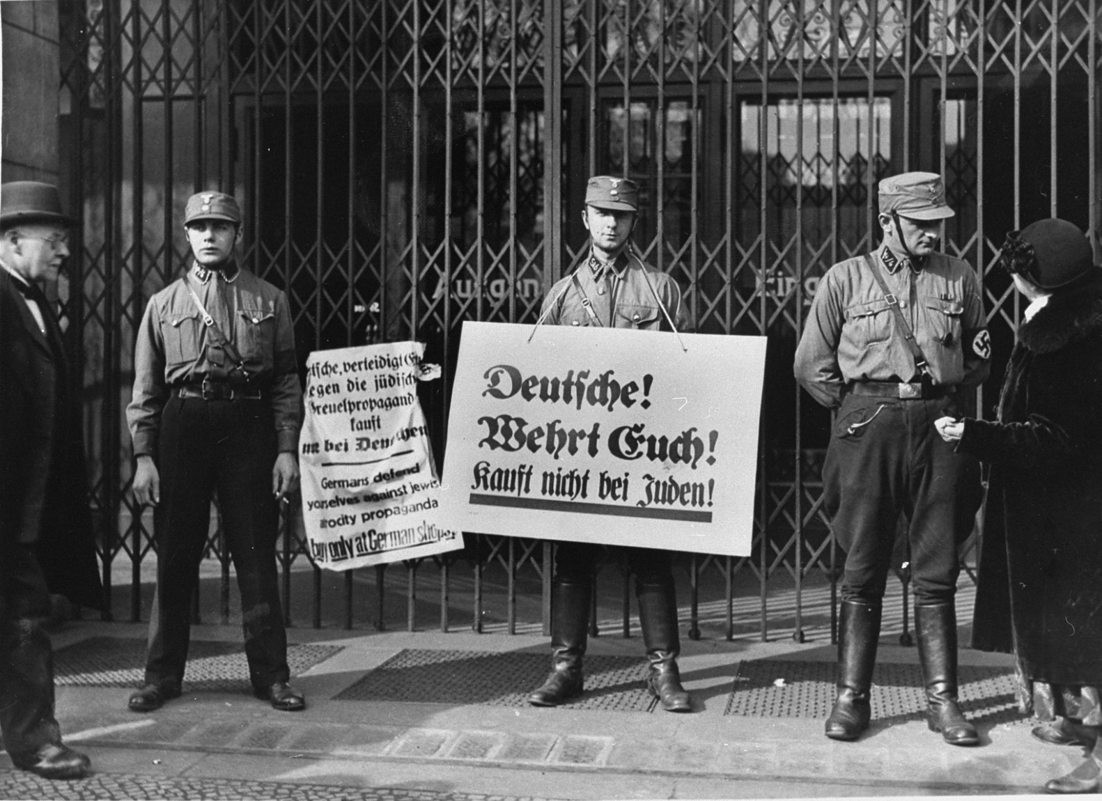 SA pickets, wearing boycott signs, block the entrance to a Jewish-owned shop.

The signs read: "Germans, defend yourselves against the Jewish atrocity propaganda, buy only at German shops!" and "Germans! Protect Yourselves! Don't buy from Jews!"