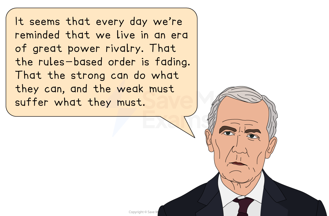 A man in a suit speaks at a microphone with a speech bubble stating concerns about power dynamics and the decline of a rules-based order.