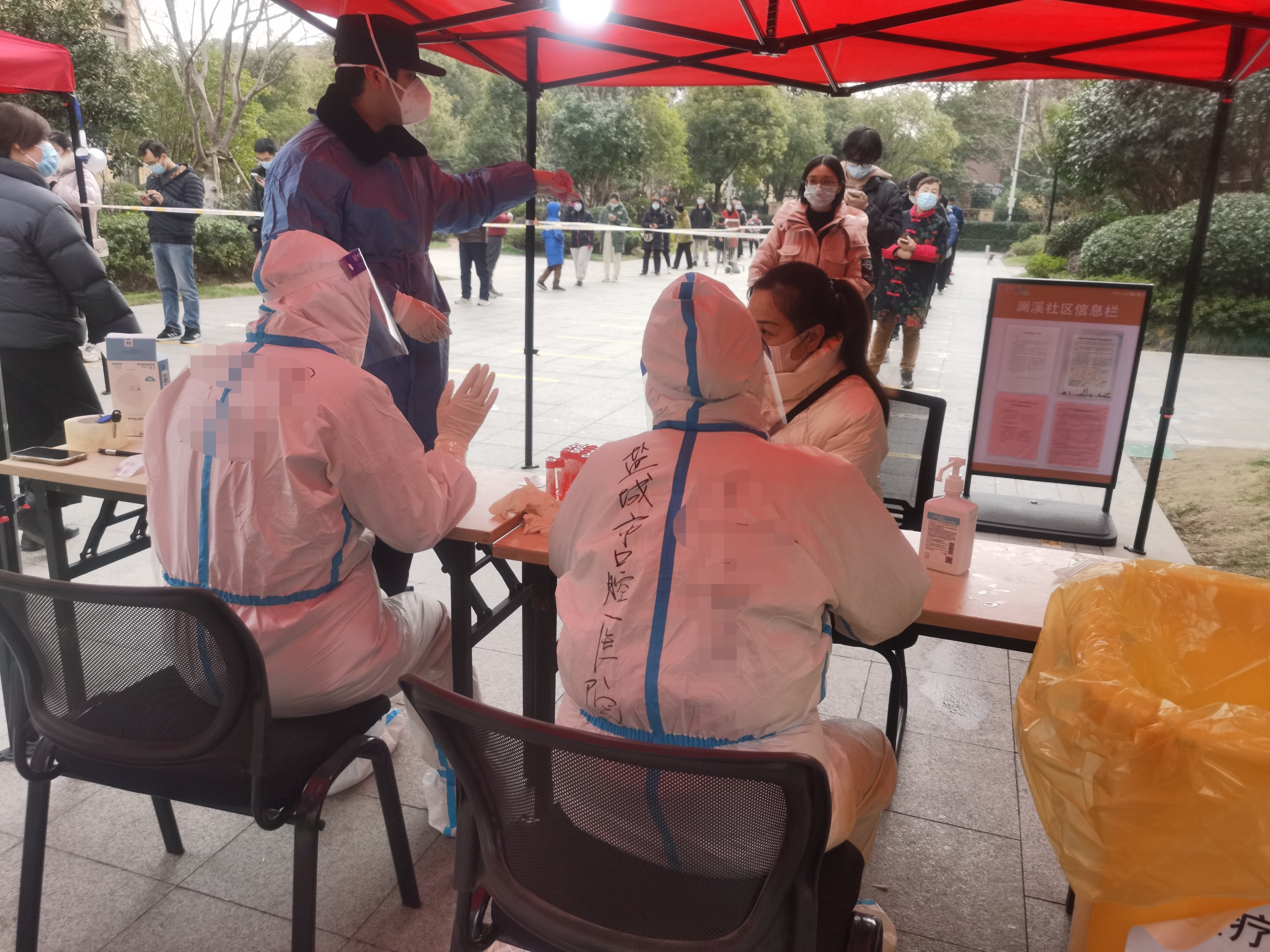 Medical staff screen Chinese people queuing to receive treatment during the Covid-19 pandemic