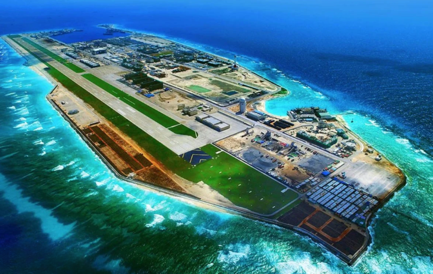 An artificially created island including an airstrip and buildings surrounded by ocean