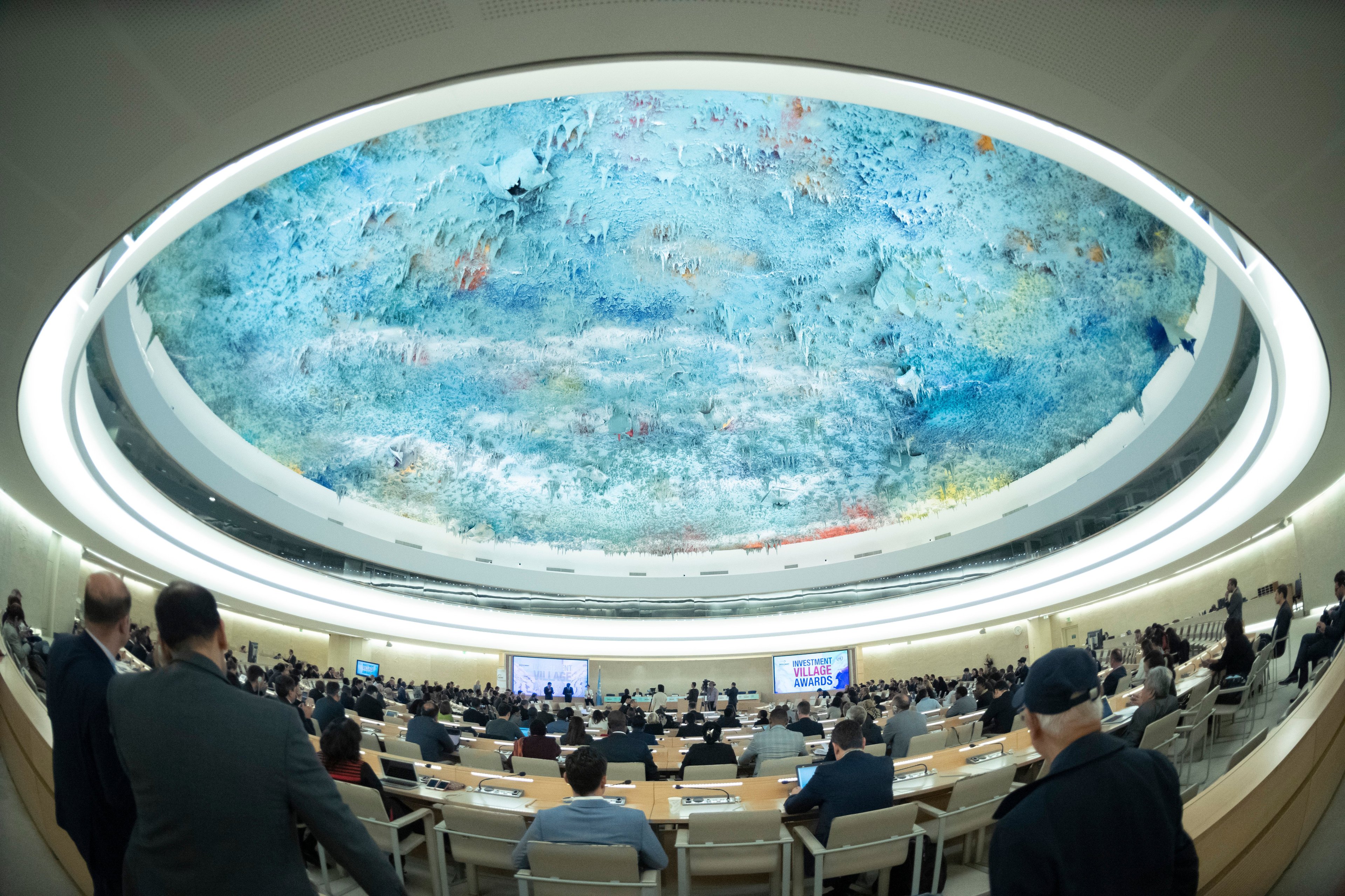 The UNHRC in session, with members sitting at desks in a circular debating chamber