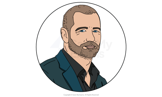 Cartoon portrait of a bearded man with short hair in a dark jacket and open-collared shirt, shown from the shoulders up in a circular frame.