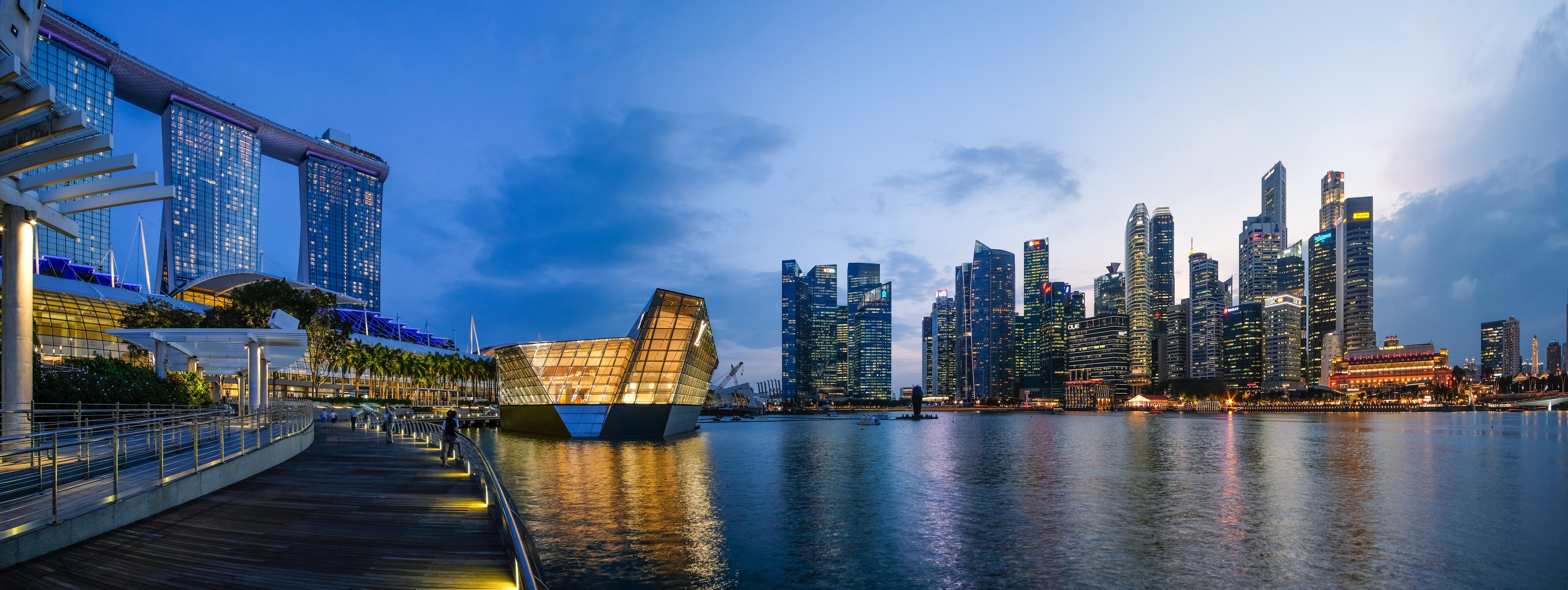 Singapore skline, looking across a waterway at dusk, with skyscrapers and modern architecture lit up