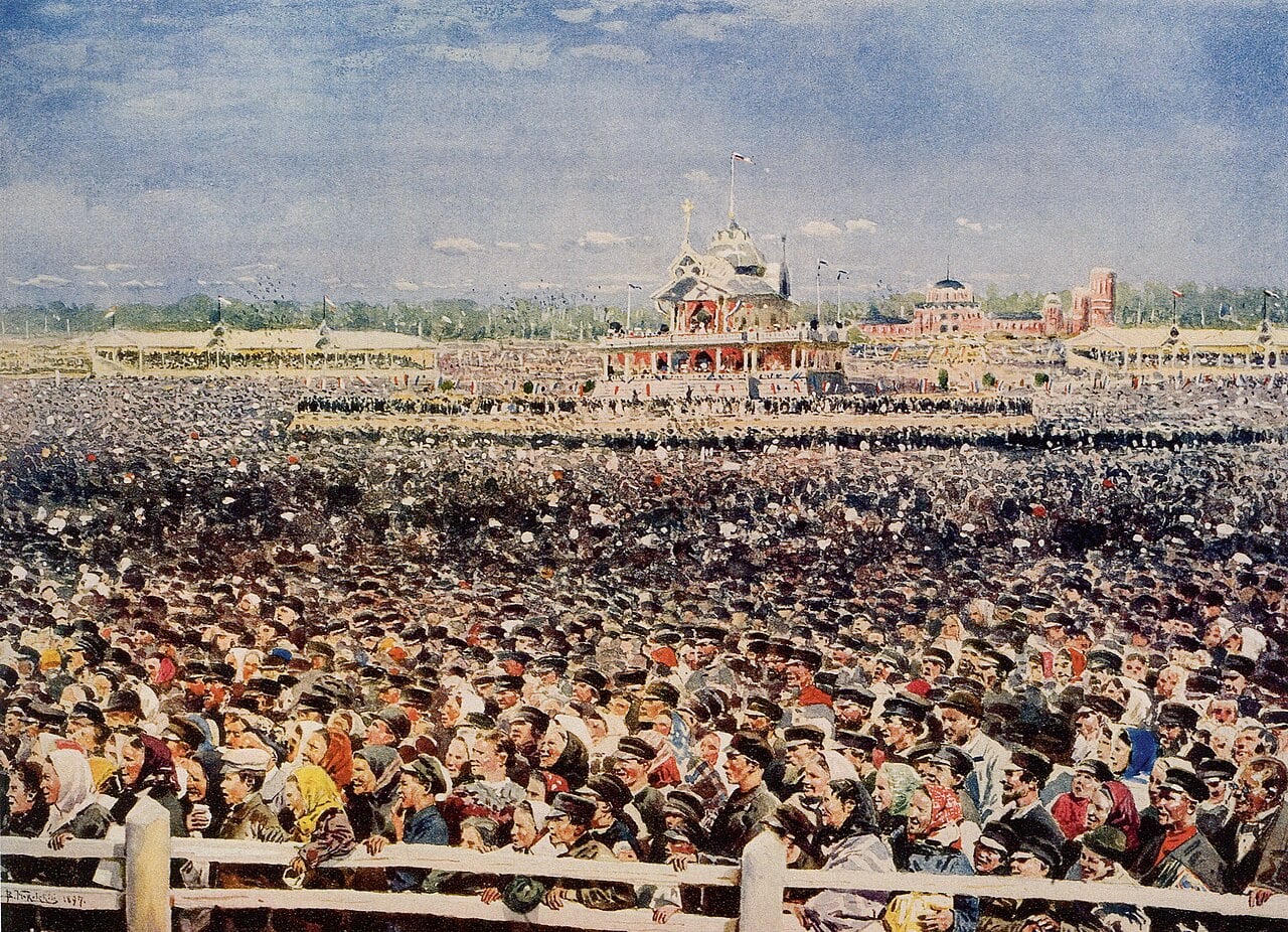 Vast crowd in traditional dress gathers at a fairground before ornate pavilions and towers under a bright, hazy sky in a detailed historical painting