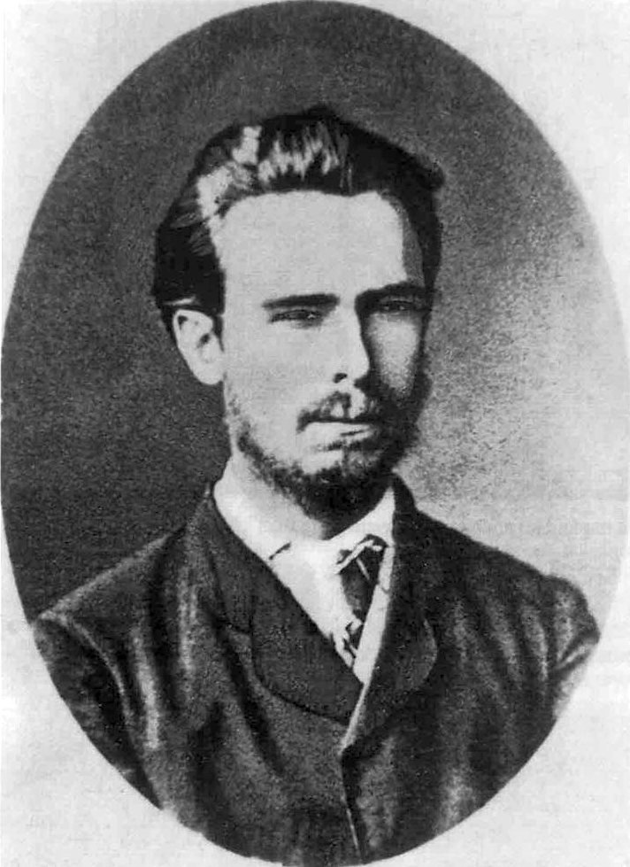 Old black-and-white studio portrait of a young bearded man in a suit and tie, facing the camera with a neutral expression, framed in an oval border