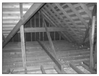 Empty house loft with exposed timber rafters, joists and boarded floor, showing roof structure in an unfinished, uninsulated attic space