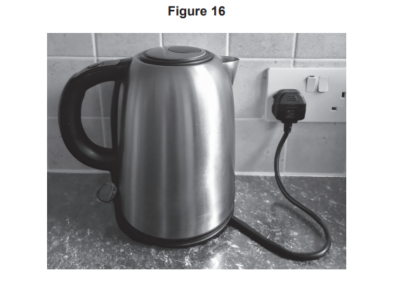 Stainless steel electric kettle on a kitchen worktop, plugged into a wall socket with cable trailing across the surface