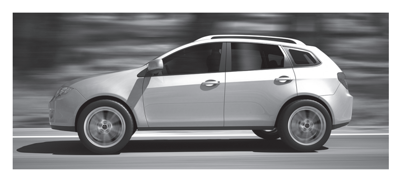 Side view of a modern estate car driving quickly along a road, motion blurred background, in black and white.