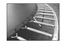 Close-up of a trampoline edge showing metal springs evenly spaced along the circular frame, attaching the taut jumping mat to the outer rim