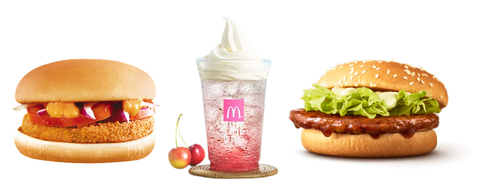 Fast food meal with a breaded chicken burger, cherry soft drink topped with ice cream and cherries, and a sesame bun burger with lettuce and sauce
