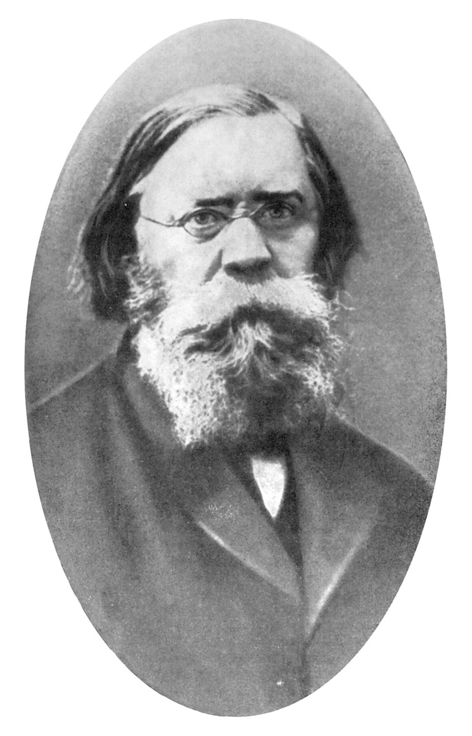 Old black-and-white portrait of a stern bearded man with spectacles, wearing a dark suit and tie, shown from the chest up in an oval frame