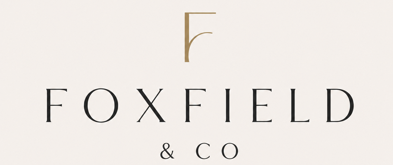 Minimalist logo reading “FOXFIELD & CO” in elegant black serif type, with a stylised gold letter F monogram above on a light cream background