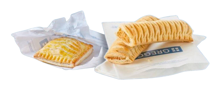 Two Greggs bakery pastries on white paper bags, including a glazed square bake and two golden flaky sausage rolls on a plain white background