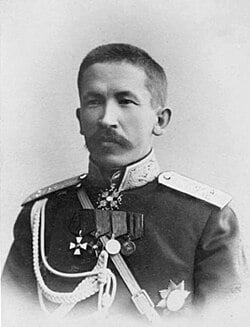 Old black-and-white portrait of a stern-faced military officer in dress uniform with epaulettes, medals and braided cords, against a plain studio background