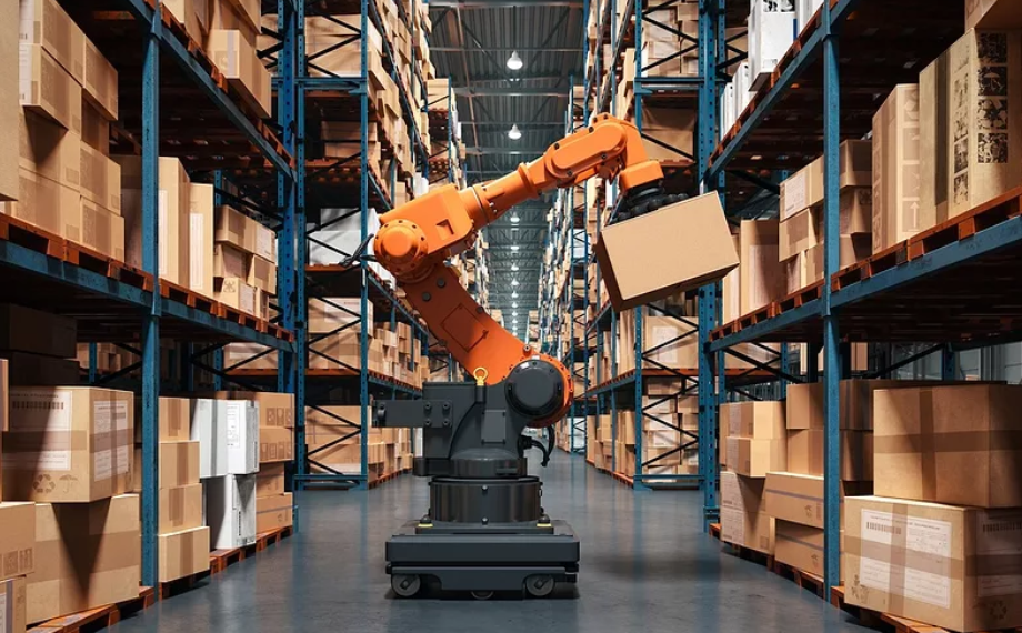 Orange robotic arm lifts a cardboard box between tall warehouse shelving racks filled with parcels under bright industrial lighting