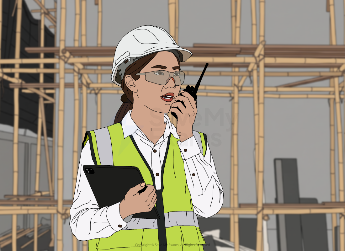 Construction site engineer in high-visibility vest and hard hat uses a walkie-talkie while holding a tablet, with scaffolding visible in the background.