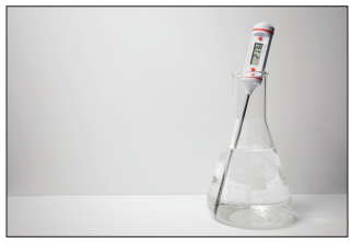Figure: Photograph of a conical flask containing a clear solution, with a digital thermometer probe inserted into the liquid