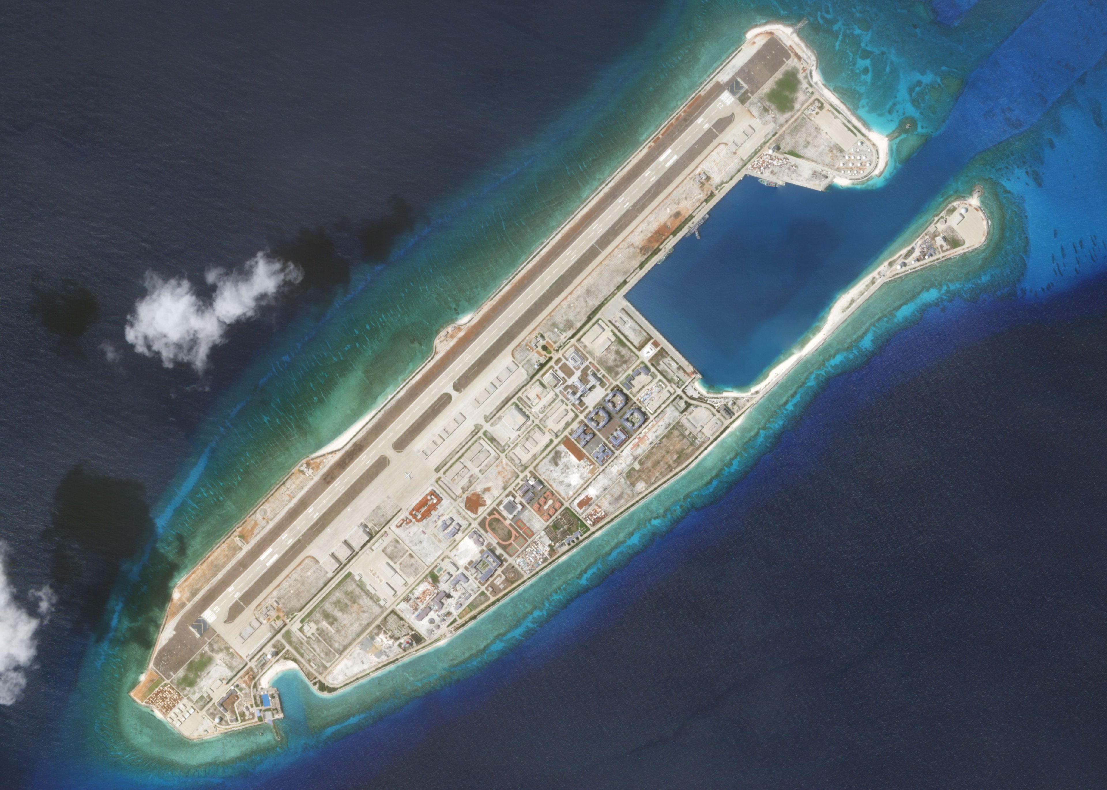 An artificially created island including an airstrip and buildings surrounded by ocean