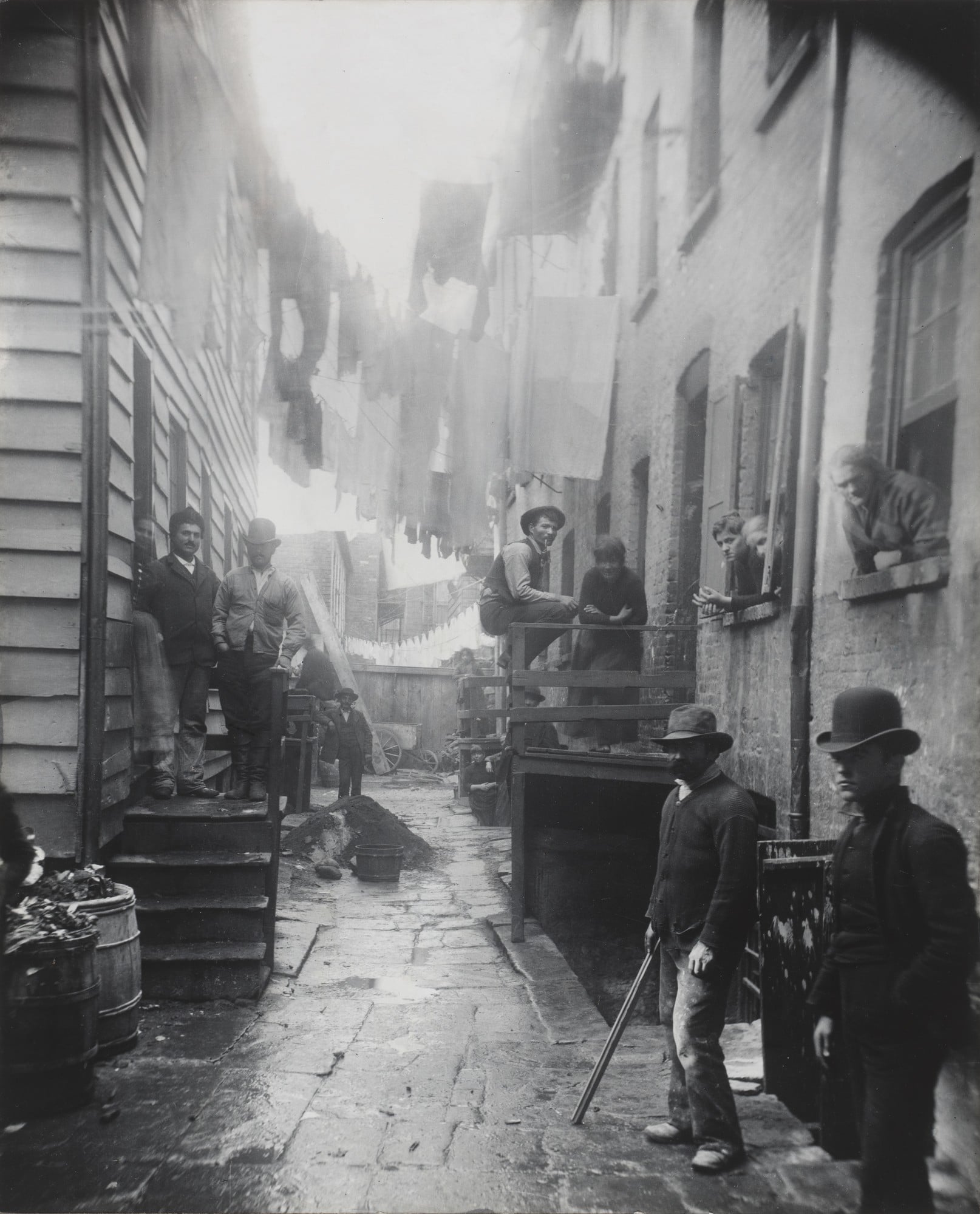 A tenement alley courtyard on the Lower East Side of Manhattan, part of Riis's How the Other Half Lives series documenting immigrant slum housing conditions.