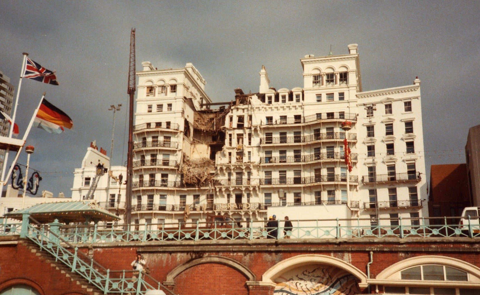 Photograph of the Grand Hotel in Brighton after the IRA bombing during the 1984 Conservative Party Conference, showing a large section of the white façade destroyed above the seafront promenade.