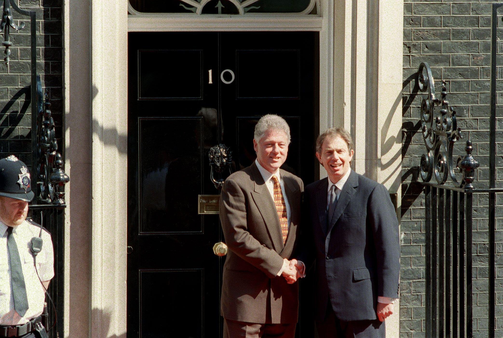 Bill Clinton and Tony Blair shake hands outside 10 Downing Street, London, both wearing suits. The photograph illustrates their close working relationship and the special relationship between the USA and Britain.